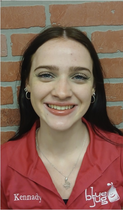Smiling woman in a red uniform shirt standing in front of a brick wall